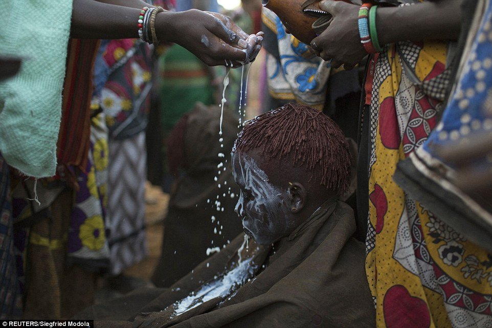 Smeared: Village elders cover a young girl's face in white paint after she is circumcised, a requirement for young girls before they can marry