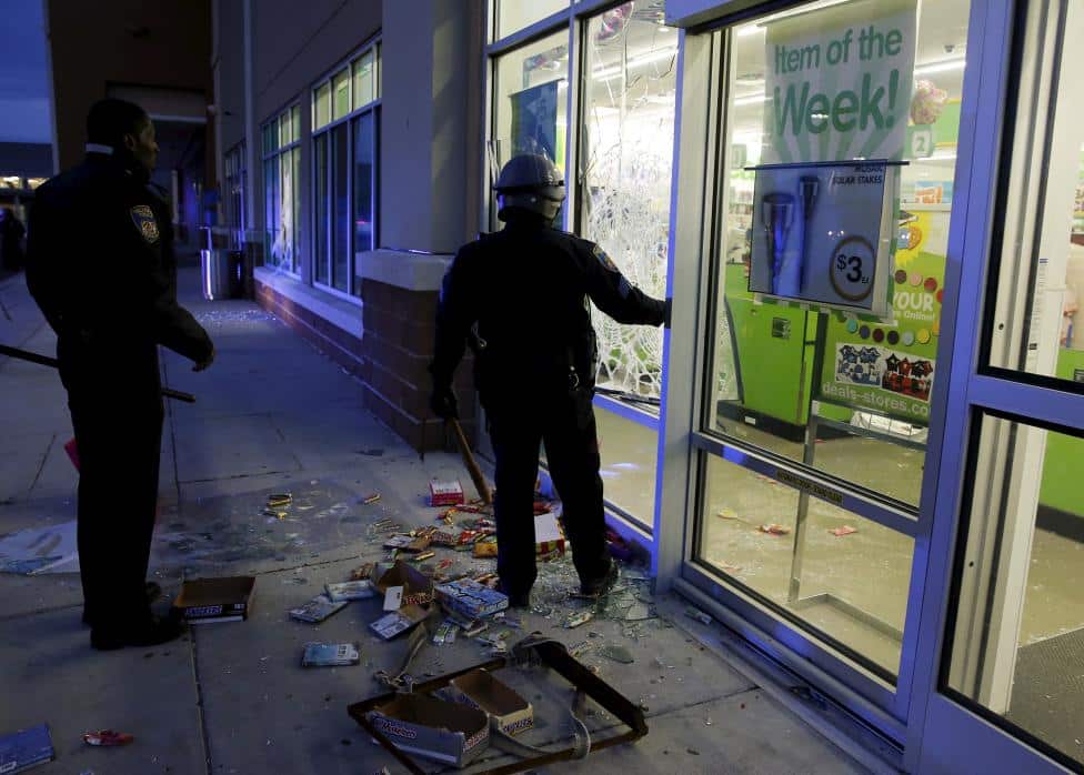 Baltimore police officers arrive at a "Deals" store that was just vandalized and looted by rioters as darkness falls during clashes between rioters and police in Baltimore