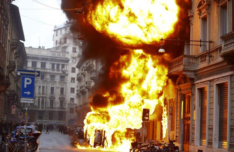 Cars are set on fire by protesters during a rally against Expo 2015 in Milan