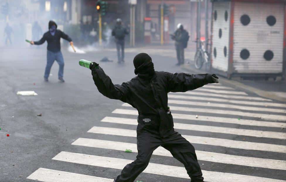 A protester throws a bottle during a rally against Expo 2015 in Milan