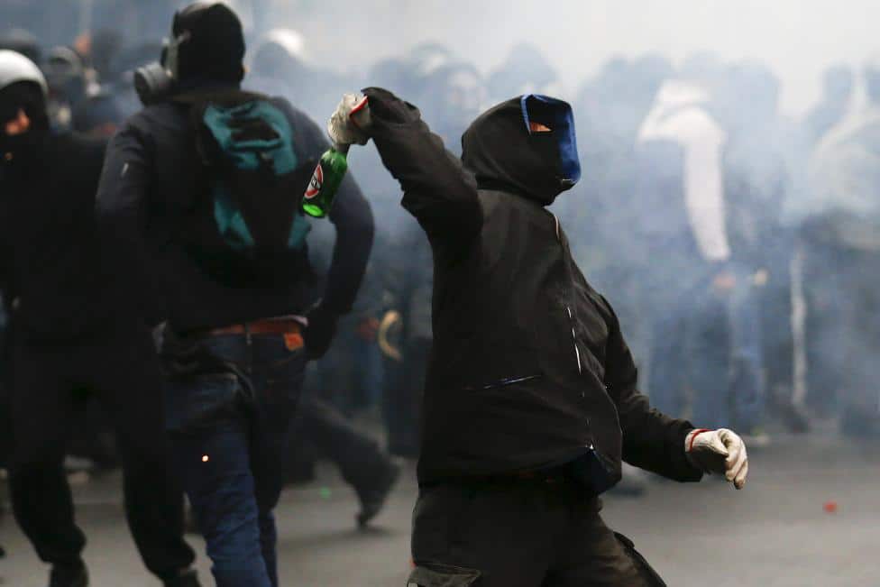 A protester throws a bottle during a rally against Expo 2015 in Milan