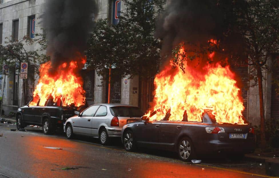 Cars are set on fire by protesters during a rally against Expo 2015 in Milan