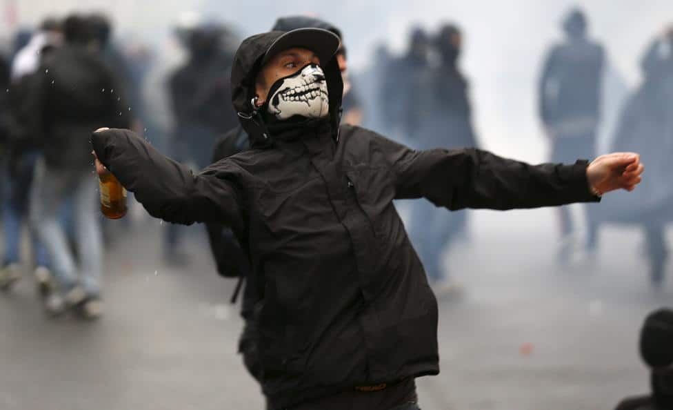 A protester throws a bottle during a rally against Expo 2015 in Milan